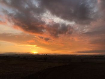 Scenic view of dramatic sky over land during sunset