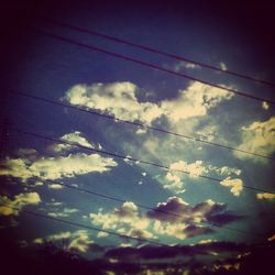 Low angle view of power lines against cloudy sky