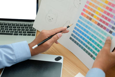 Cropped hand of businessman holding color swatch in office