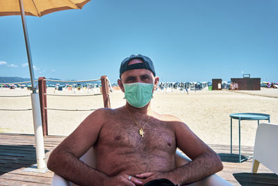 Man sitting at beach against clear sky