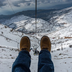 Low section of person over snow covered landscape