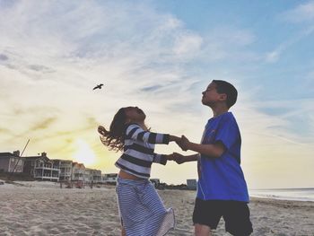 Woman standing on beach at sunset