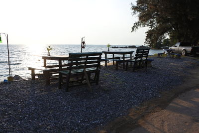 Bench on beach against clear sky