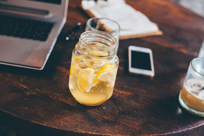 High angle view of lemonade in jar by laptop and mobile phone on table