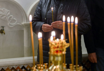 Midsection of woman holding illuminated candles