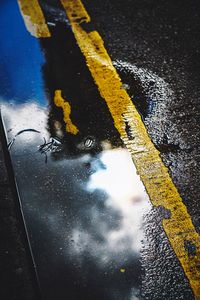 High angle view of yellow umbrella on wet road