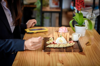 Midsection of woman having food on table