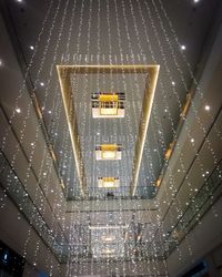 Low angle view of illuminated lights hanging on ceiling in building