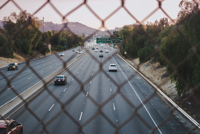 Cars on street seen through chainlink fence