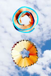 Low angle view of pencil shavings levitation against sky