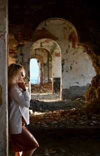 Side view of woman standing in abandoned building