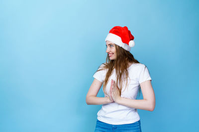 Young woman wearing hat standing against blue background