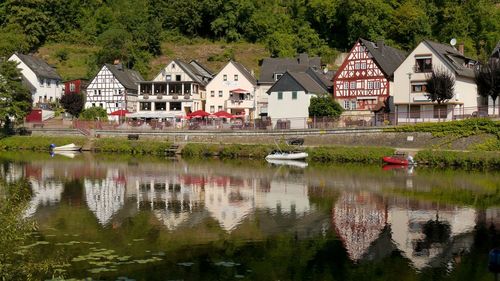 Houses by lake and buildings against trees