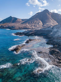 Scenic view of sea and mountains against sky