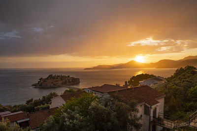 High angle view of sea and buildings against sky during sunset