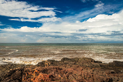 Rocky sea beach with crashing waves at morning from flat angle