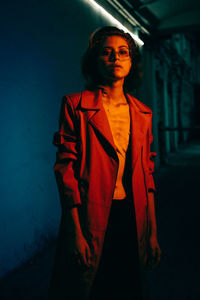 Young woman looking away while standing against wall