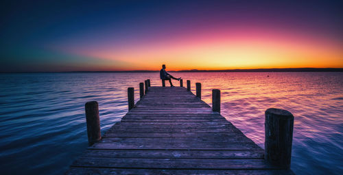 Silhouette pier over sea against sky during sunset