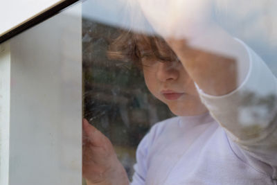 Portrait of boy looking through glass window