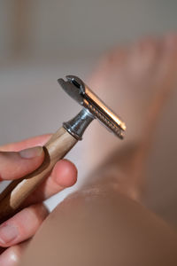 Female hand holding safety razor shaving leg