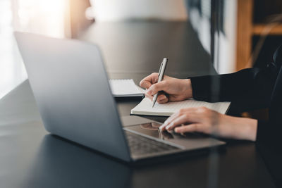 Midsection of woman using laptop on table