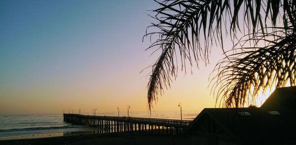 Silhouette built structure on beach against clear sky