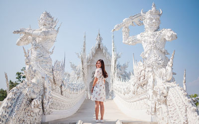 Full length portrait of woman standing by temple against sky