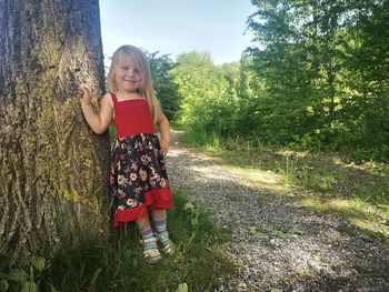 Full length portrait of girl with arms raised on tree