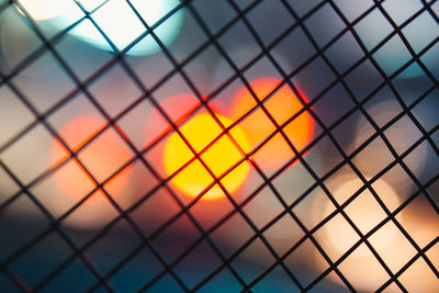 Close-up of chainlink fence against orange sky