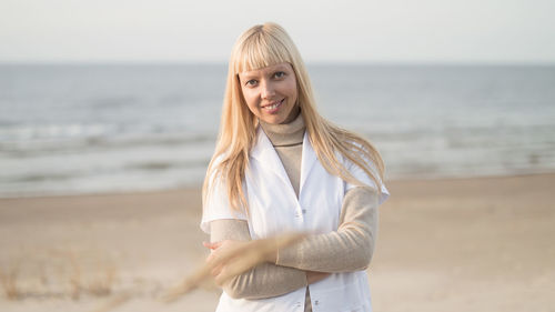 Portrait of young woman standing at beach