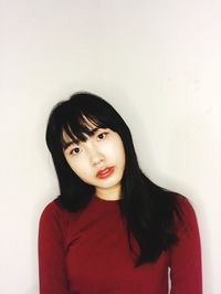 Portrait of beautiful young woman standing against wall