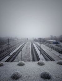 Snow covered railroad tracks against sky during winter