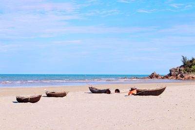 People relaxing on beach against sky