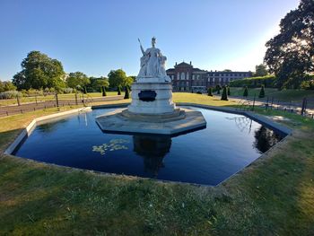 Statue by lake against sky