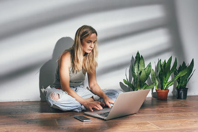 Woman working on laptop while sitting on floor at home