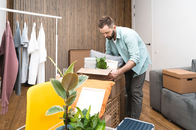 Mature man unpacking things from boxes while moving in new apartment.