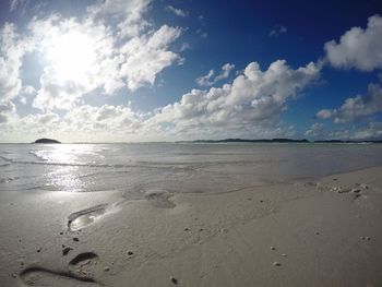 View of calm beach against cloudy sky