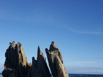 Low angle view of rock formation against clear blue sky