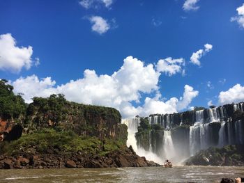 View of waterfall against cloudy sky