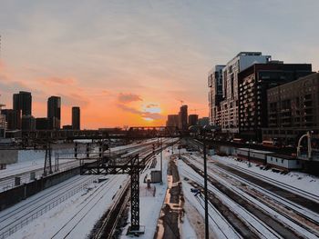 High angle view of railroad tracks amidst buildings against sky during sunset