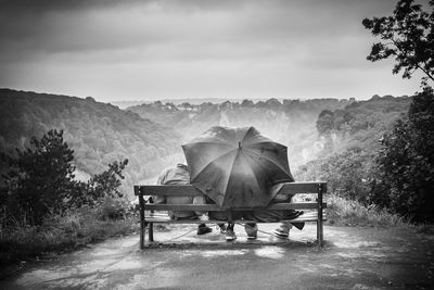 Bristol, uk - 20 august 2017. black and white image of friends on a bench under a large umbrella. 