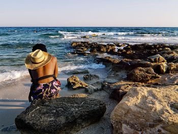 Rear view of man looking at sea shore against sky