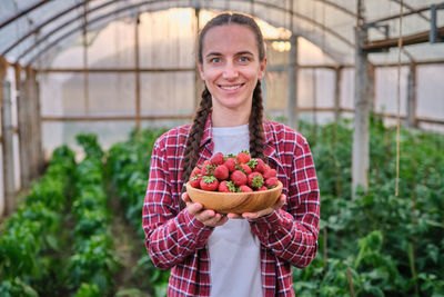 Portrait of young woman standing in greenhouse