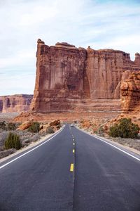 Rock formations by road against sky