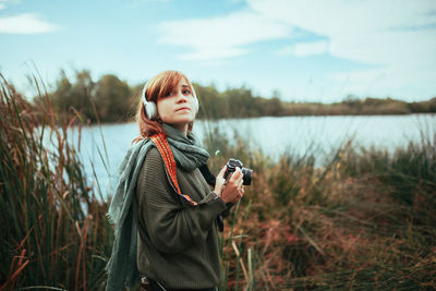 Young woman taking photos near to lake with an old analog camera