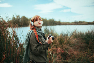 Portrait of beautiful woman standing by lake against sky