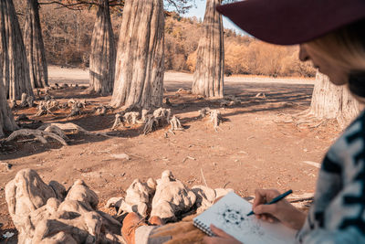 Midsection of man on rock in forest