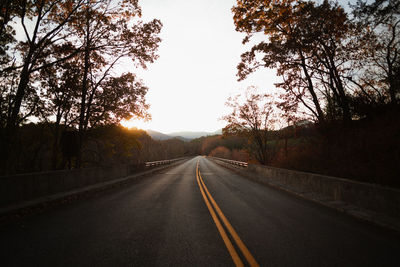 Empty road against sky during sunset