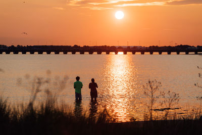 Silhouette men against sky during sunset