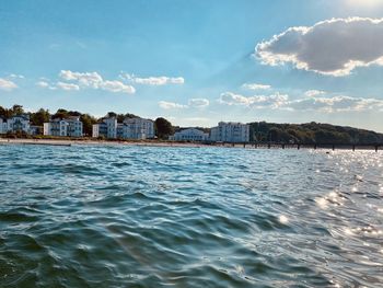 Scenic view of sea by buildings against sky